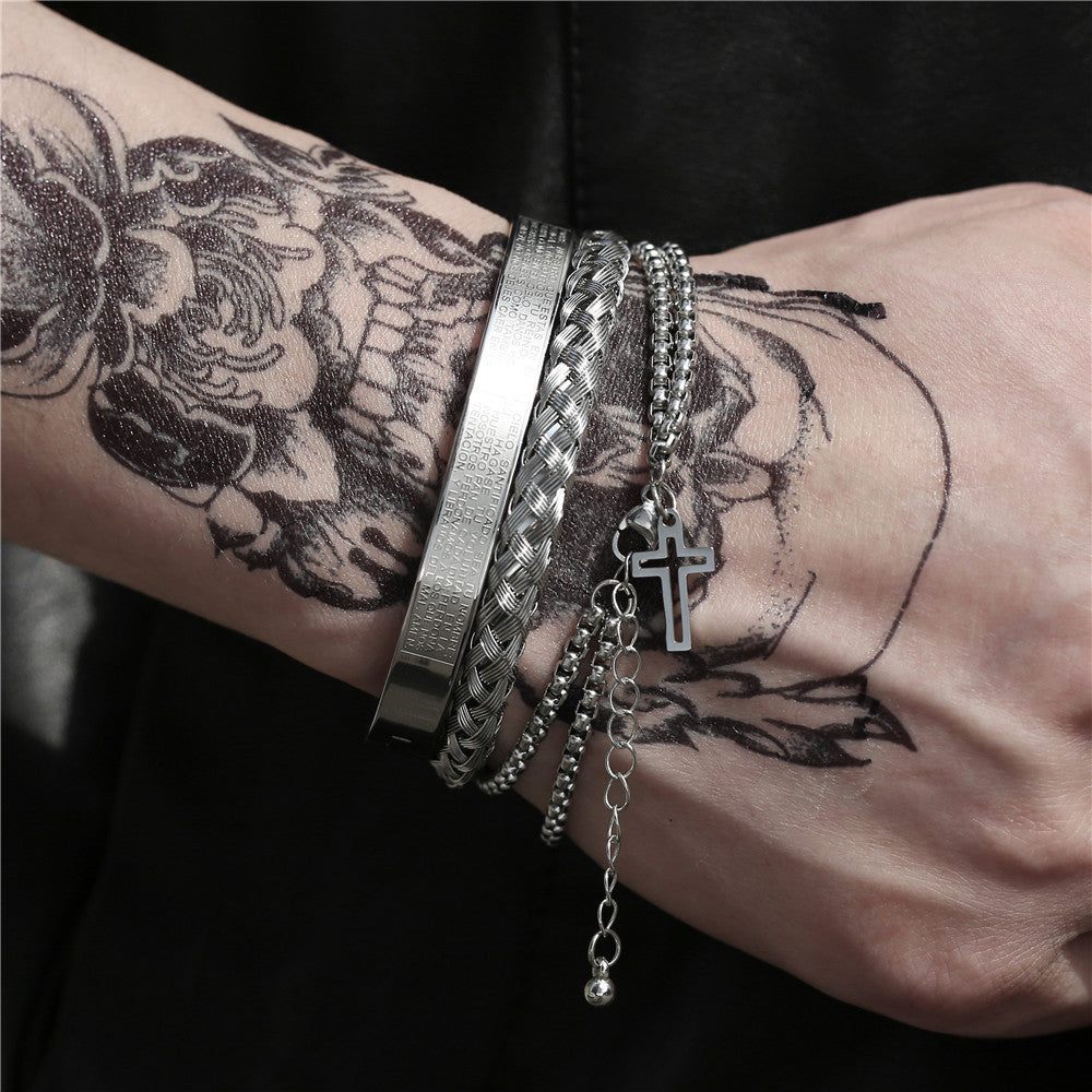 Wrist with multiple silver bracelets and a cross charm against a dark background