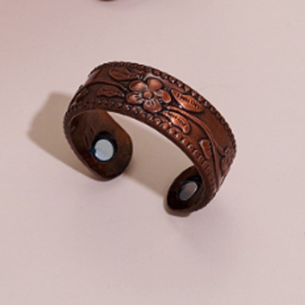 Brown leather cuff bracelet with embossed design on a beige background