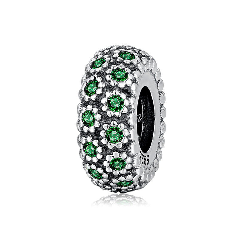 Silver charm with green gemstones on a white background