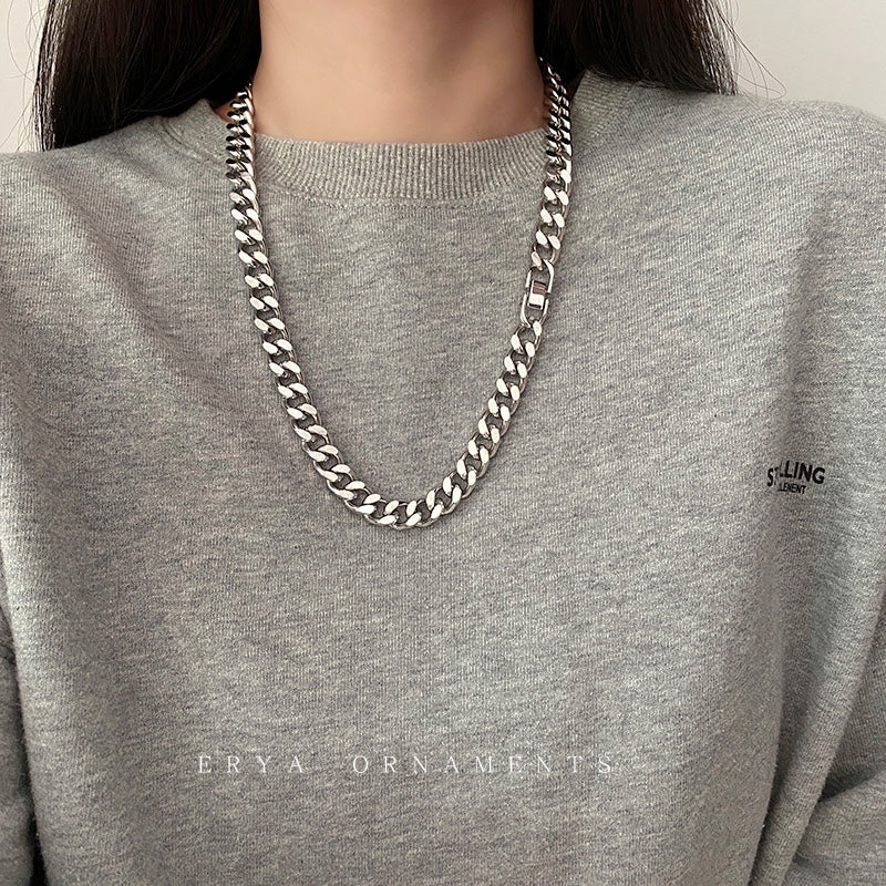 Person wearing a silver chain necklace on a gray sweatshirt with 'ERYA ORNAMENTS' branding.