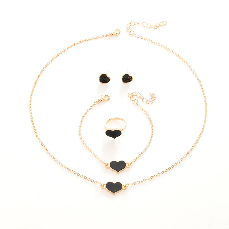Jewelry set with gold necklaces, bracelets, and earrings with black heart-shaped charms on a white background.