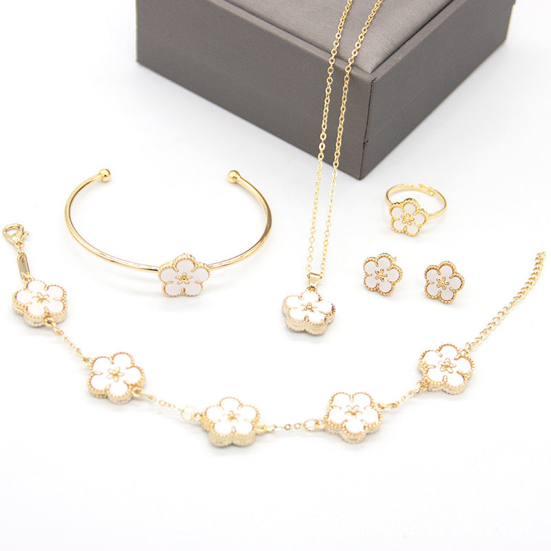 Gold jewelry set with floral designs including necklace, bracelet, ring, and earrings on a white background.