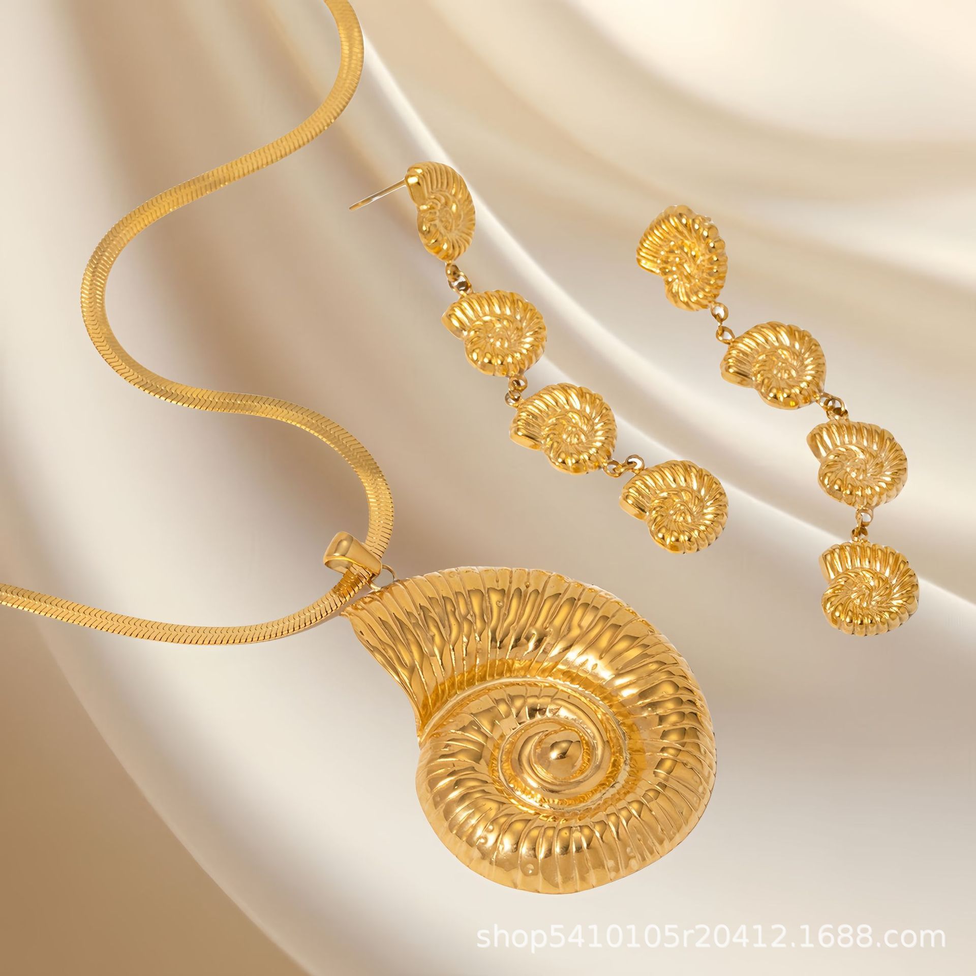 Gold necklace and earrings on a beige fabric background
