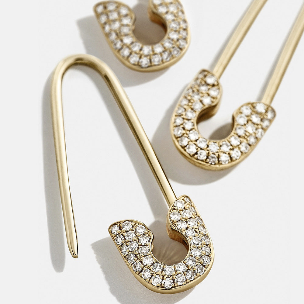 Gold earrings with clear gemstones on a white background