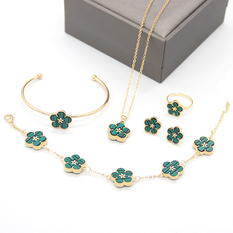 Gold and green floral jewelry set on a white background