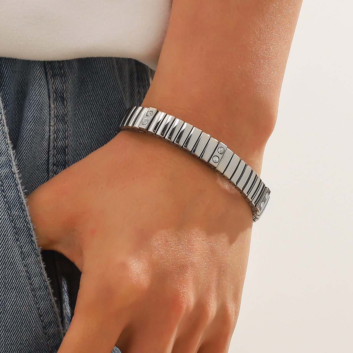 Silver bracelet on a wrist with a neutral background