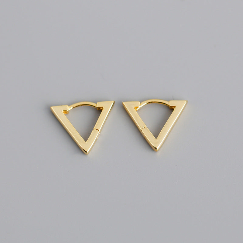 Pair of gold triangle-shaped earrings on a gray background