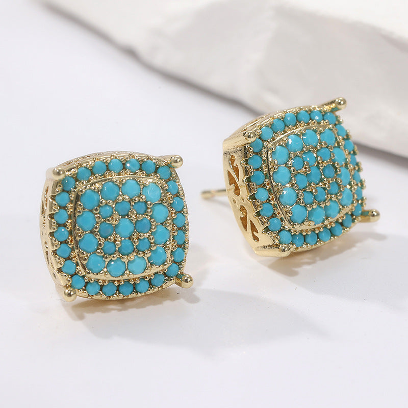 Gold earrings with turquoise stones on a white background