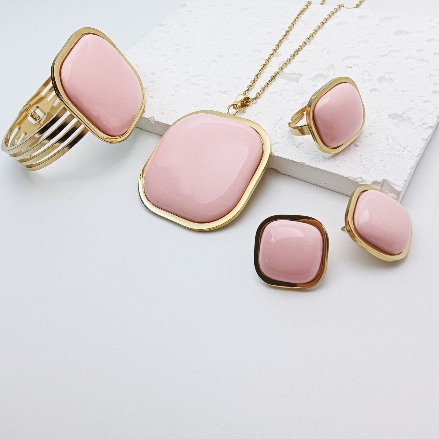 Jewelry set with pink stones and gold accents on a light background