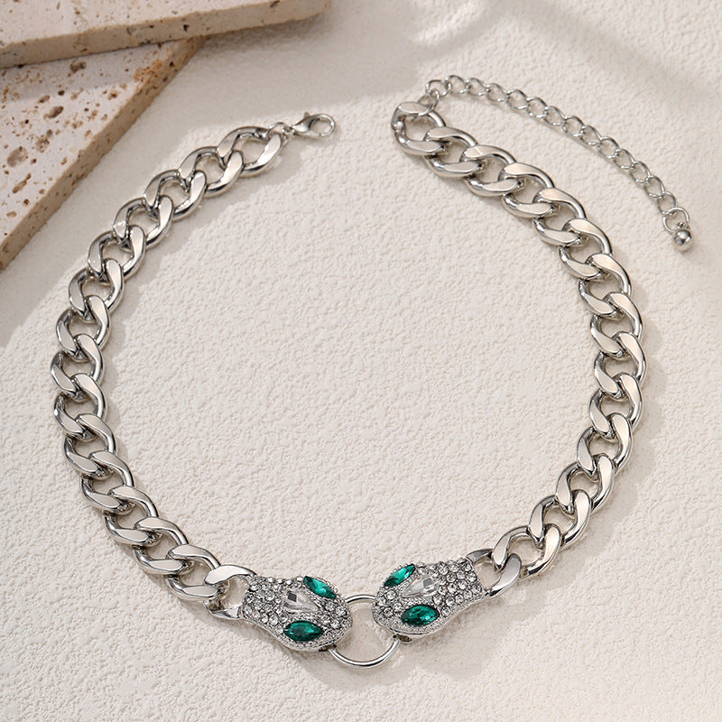 Silver chain necklace with green gemstones on a light background