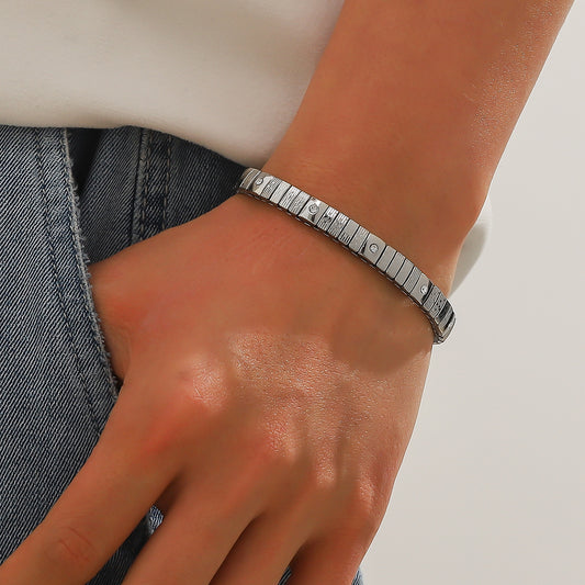 Silver bracelet on a wrist with a neutral background