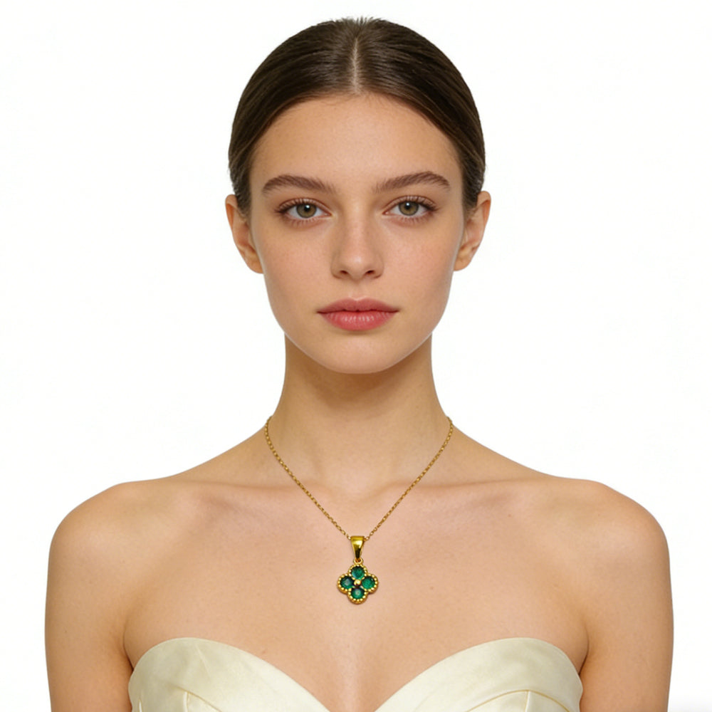 Woman wearing a gold necklace with a green pendant on a white background