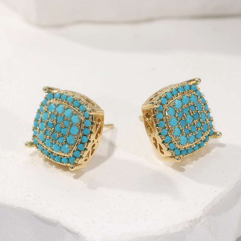 Gold earrings with turquoise stones on a white background