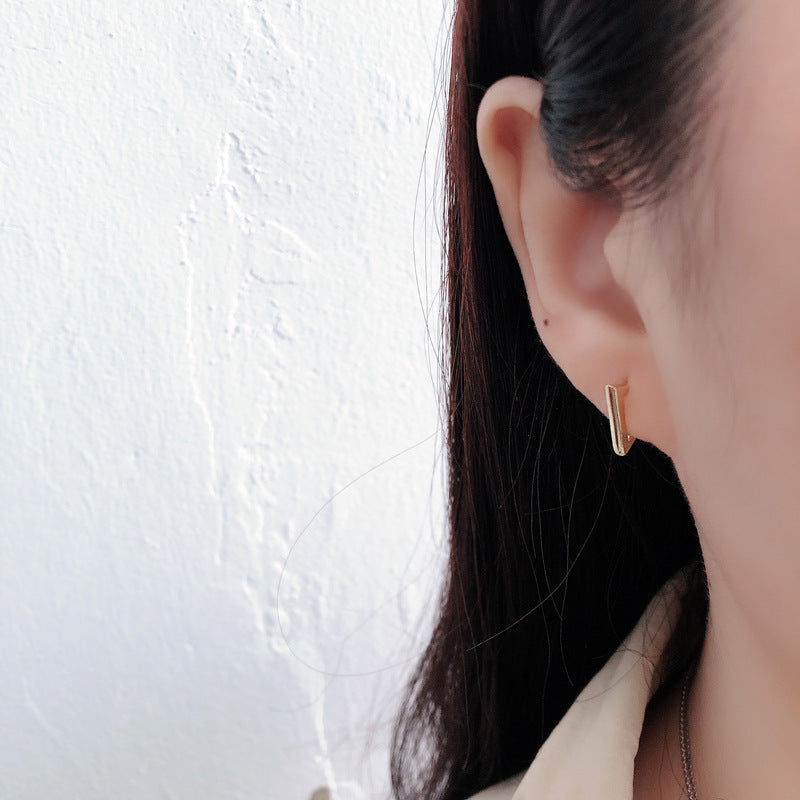 Gold hoop earring worn by a person against a white background
