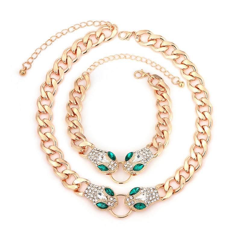Gold chain necklace with green and clear gemstones on a white background