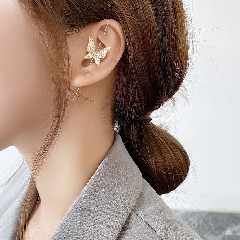 Butterfly-shaped earrings worn by a person with a blurred background