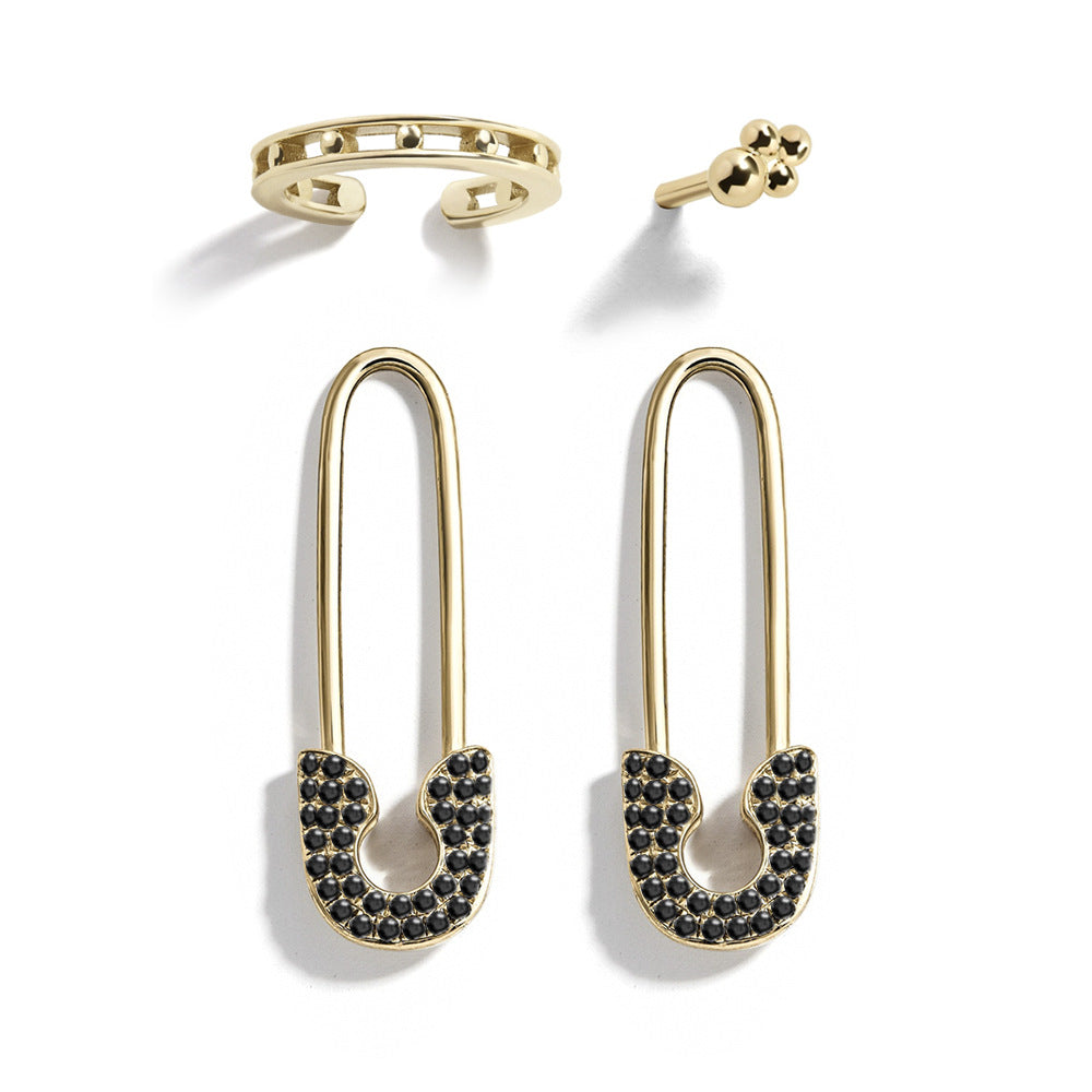 Gold safety pin earrings with black gemstones on a white background