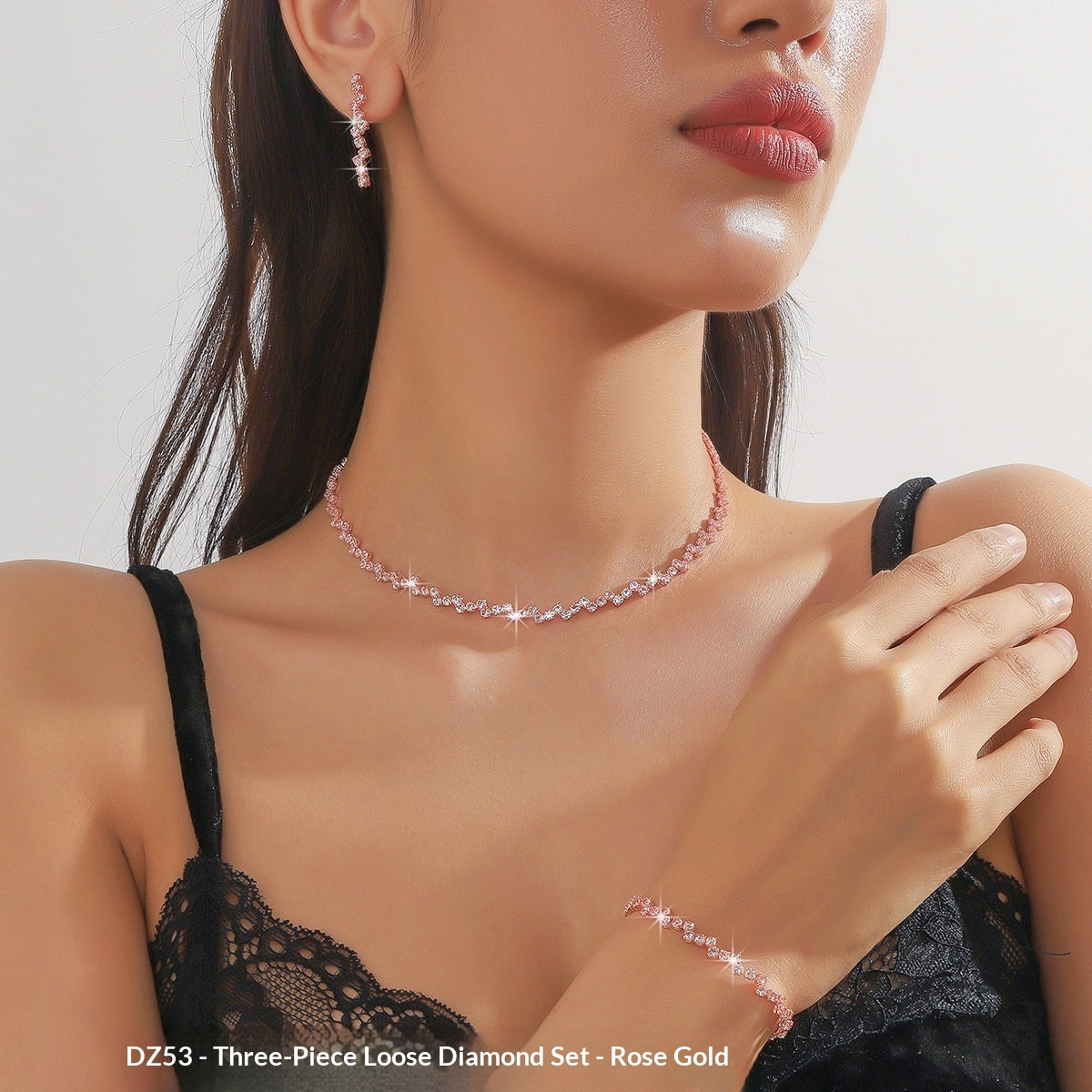 Woman wearing a rose gold necklace, earrings, and bracelet set against a neutral background.