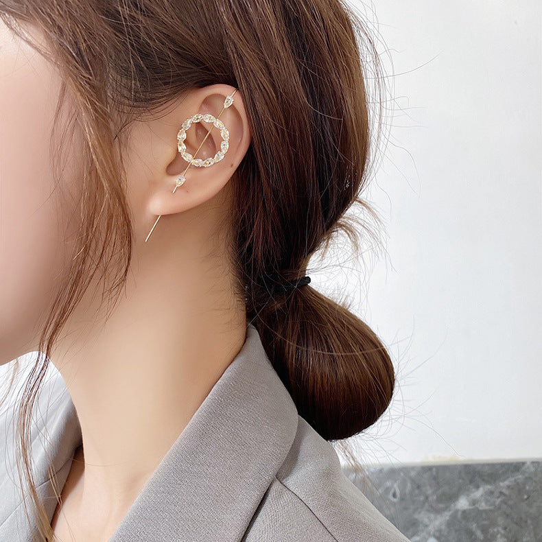 Close-up of an ear with a decorative earring against a neutral background
