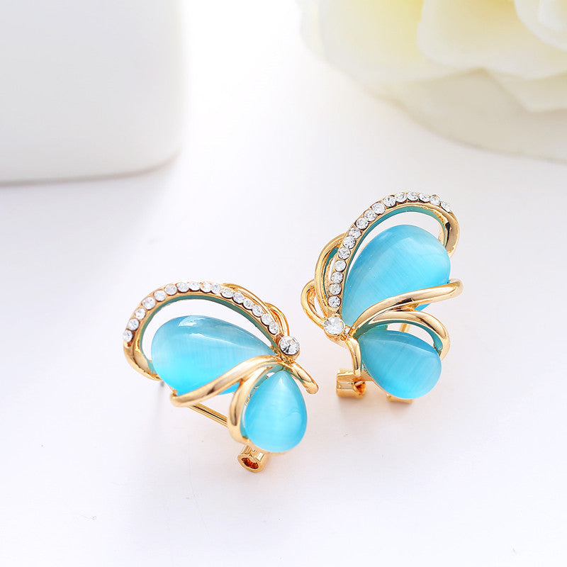 Pair of butterfly-shaped earrings with blue stones and gold accents on a white background.