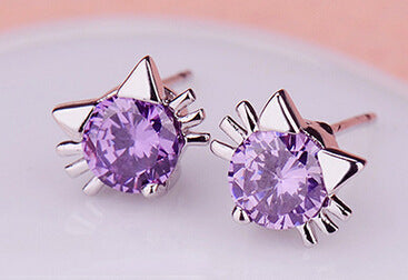 Pair of purple gemstone earrings with silver star-shaped settings on a light background
