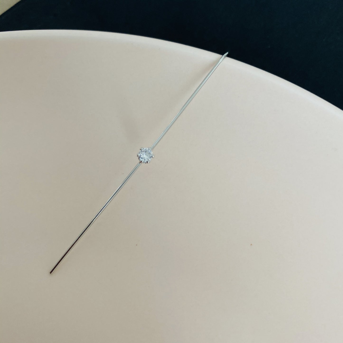 Diamond earring on a beige cushion with a black background