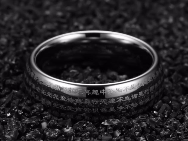 Silver ring with engraved text on a dark textured background