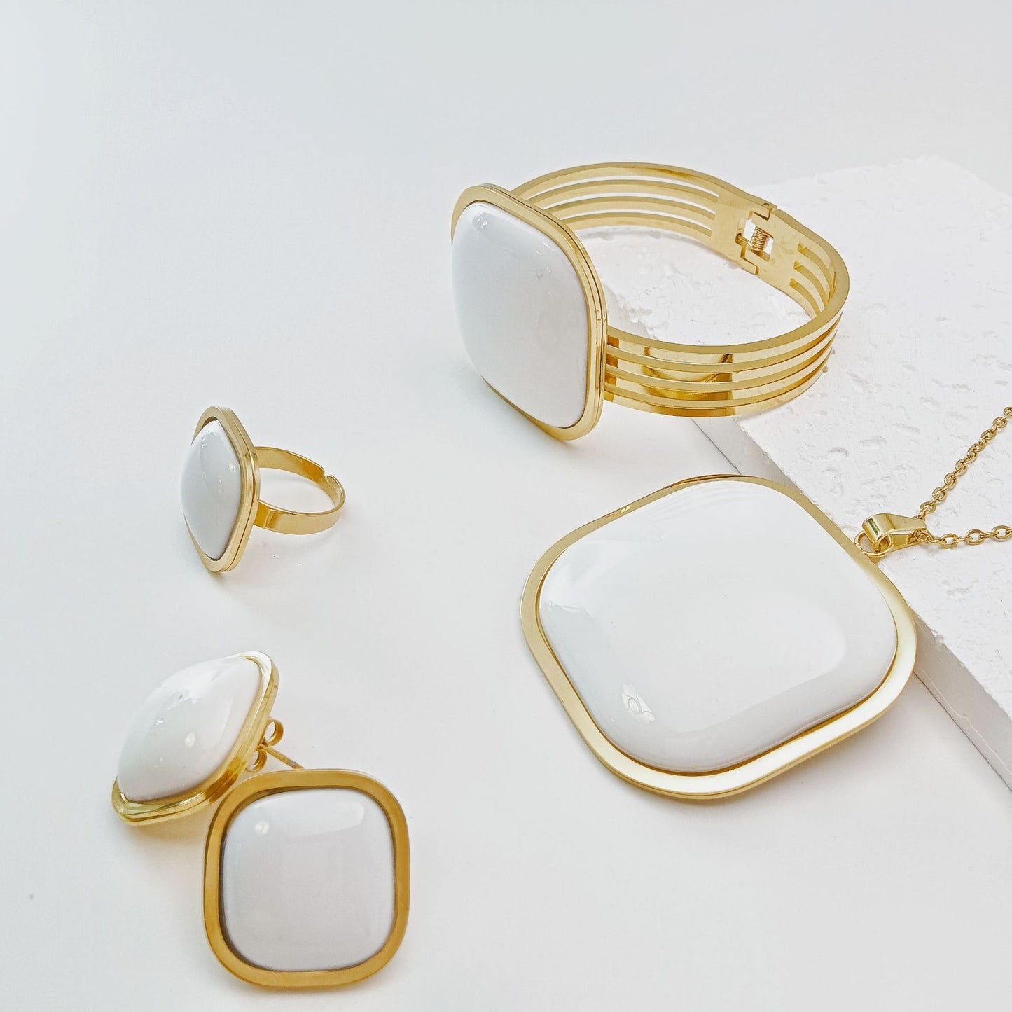 Gold and white jewelry set including necklace, ring, and earrings on a light background