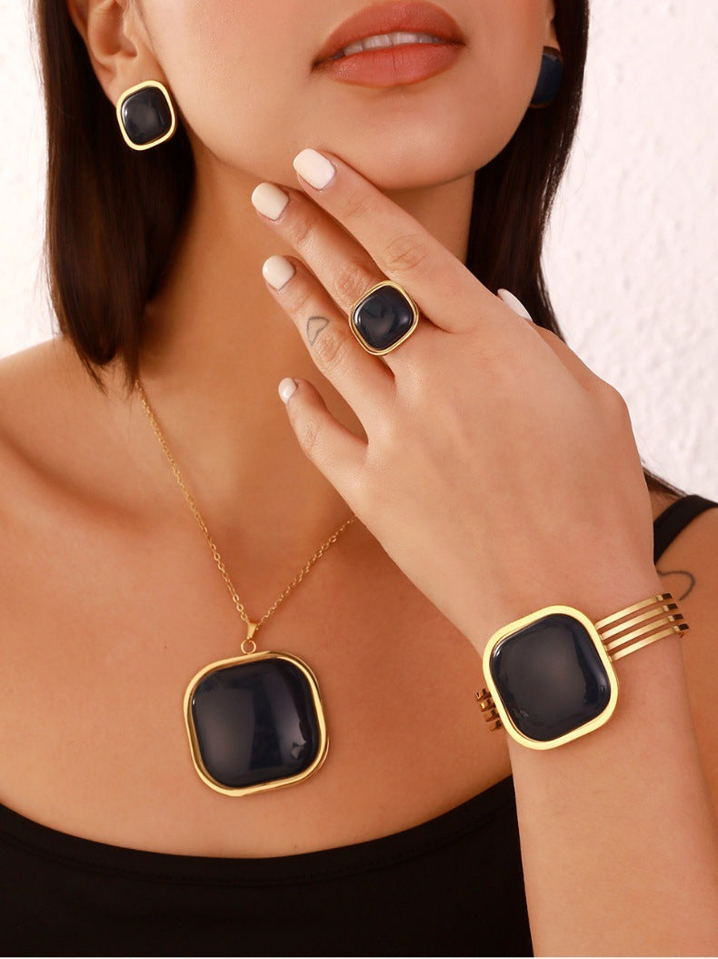 Jewelry set with necklace, ring, and bracelet featuring black stones and gold accents.