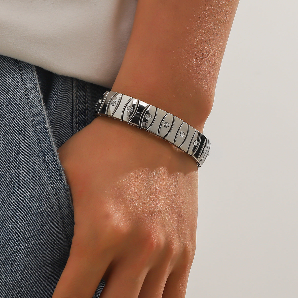 Silver bracelet on a wrist with a neutral background