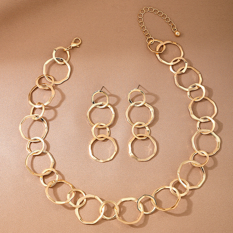Gold chain necklace and earrings on a beige background