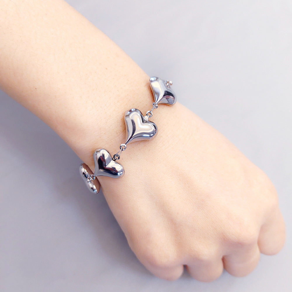 Silver heart-shaped bracelet on a child's wrist against a light gray background