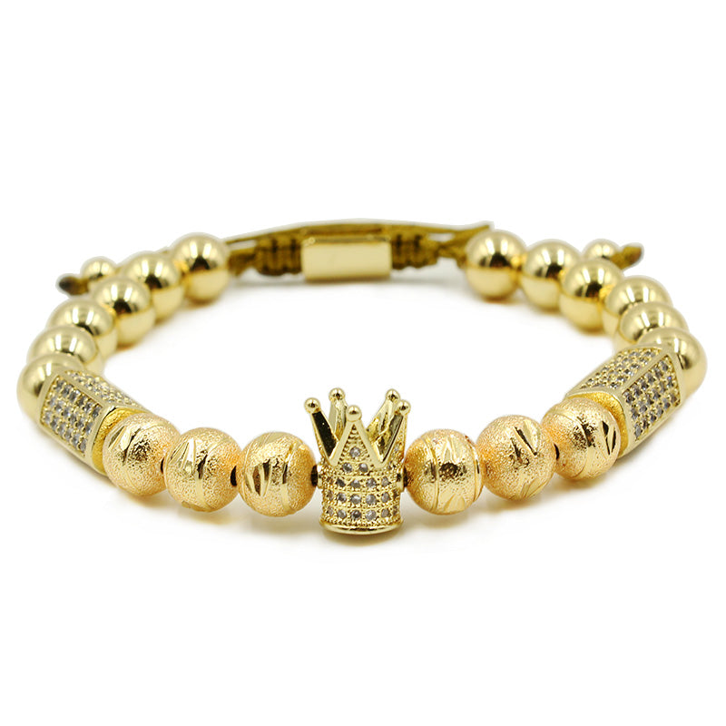 Gold bracelet with crown charm on a white background