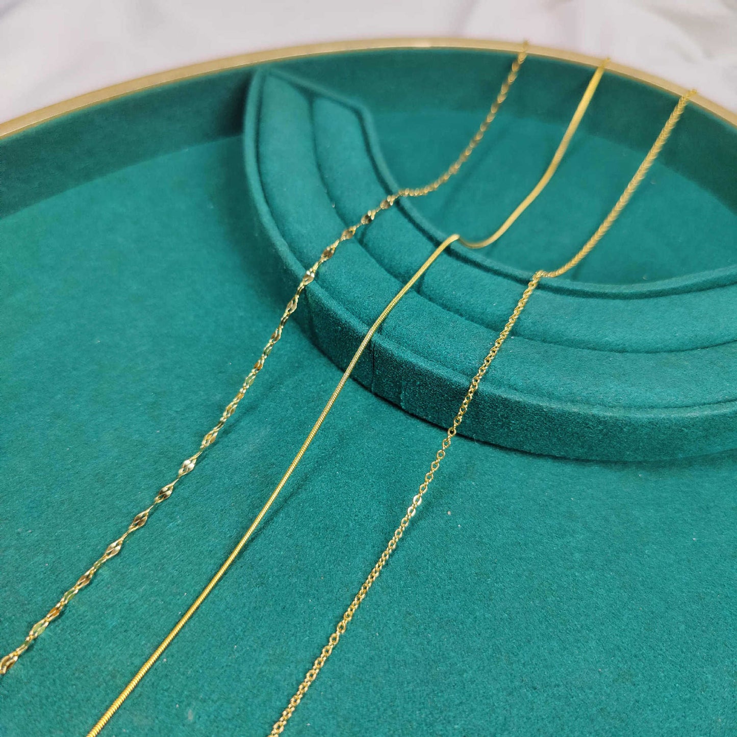 Gold chain on a green jewelry display tray