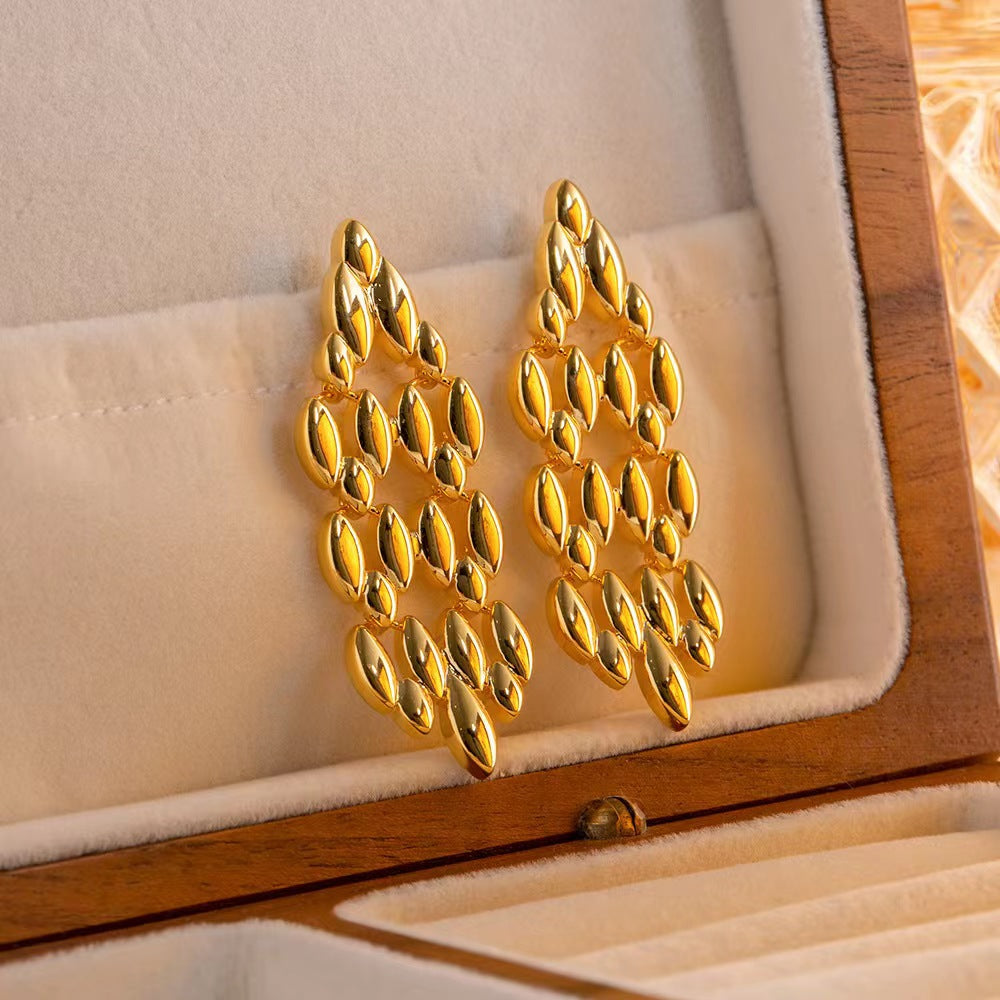 Gold earrings in a wooden jewelry box with a soft beige interior