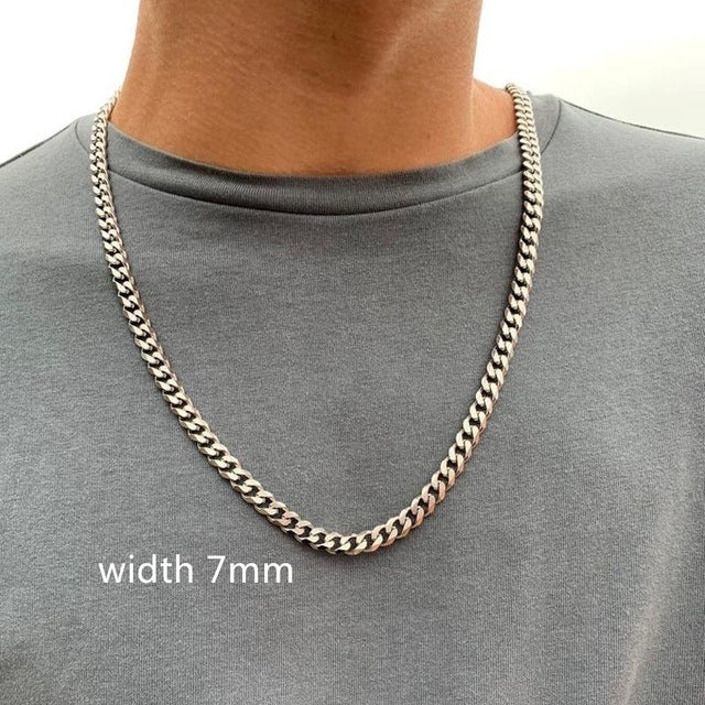 Gold chain necklace worn by a person on a gray shirt, with text indicating width 7mm.