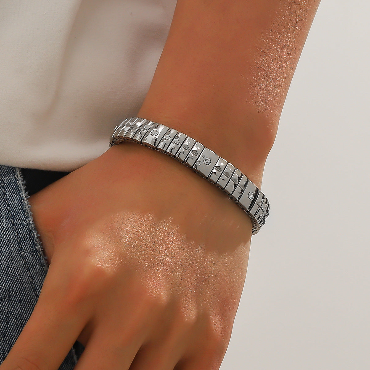 Silver bracelet on a wrist with a neutral background