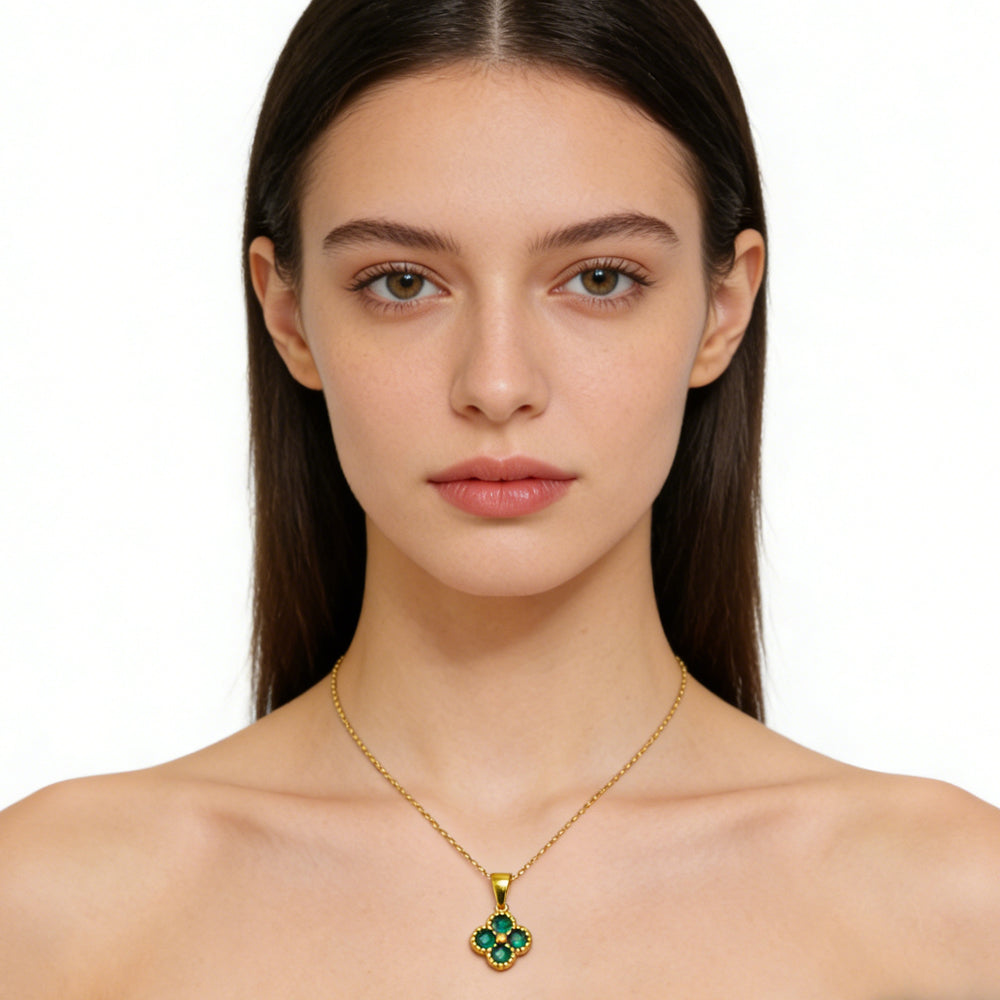 Woman wearing a gold necklace with a green pendant on a white background