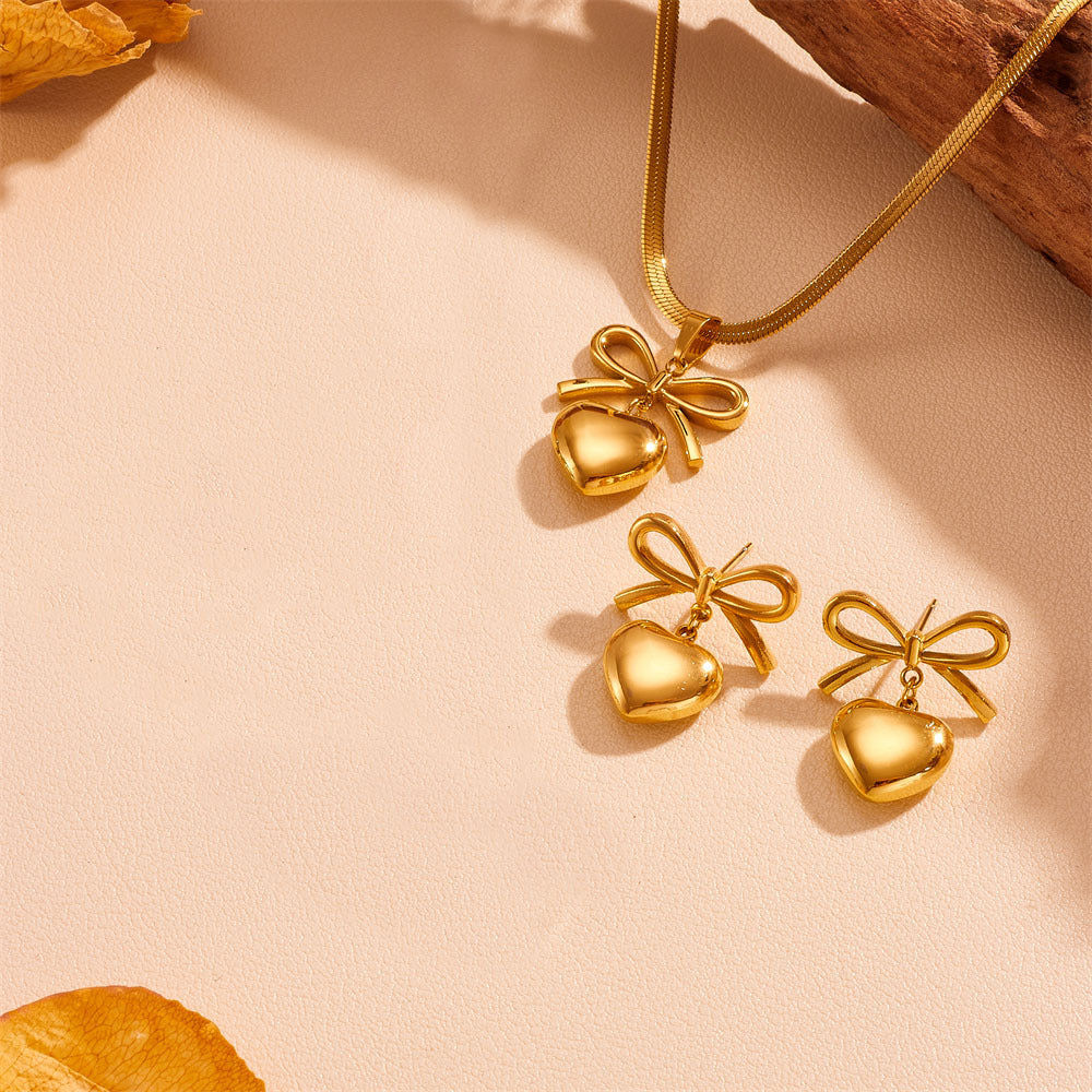 Gold heart-shaped jewelry set with bows on a beige background