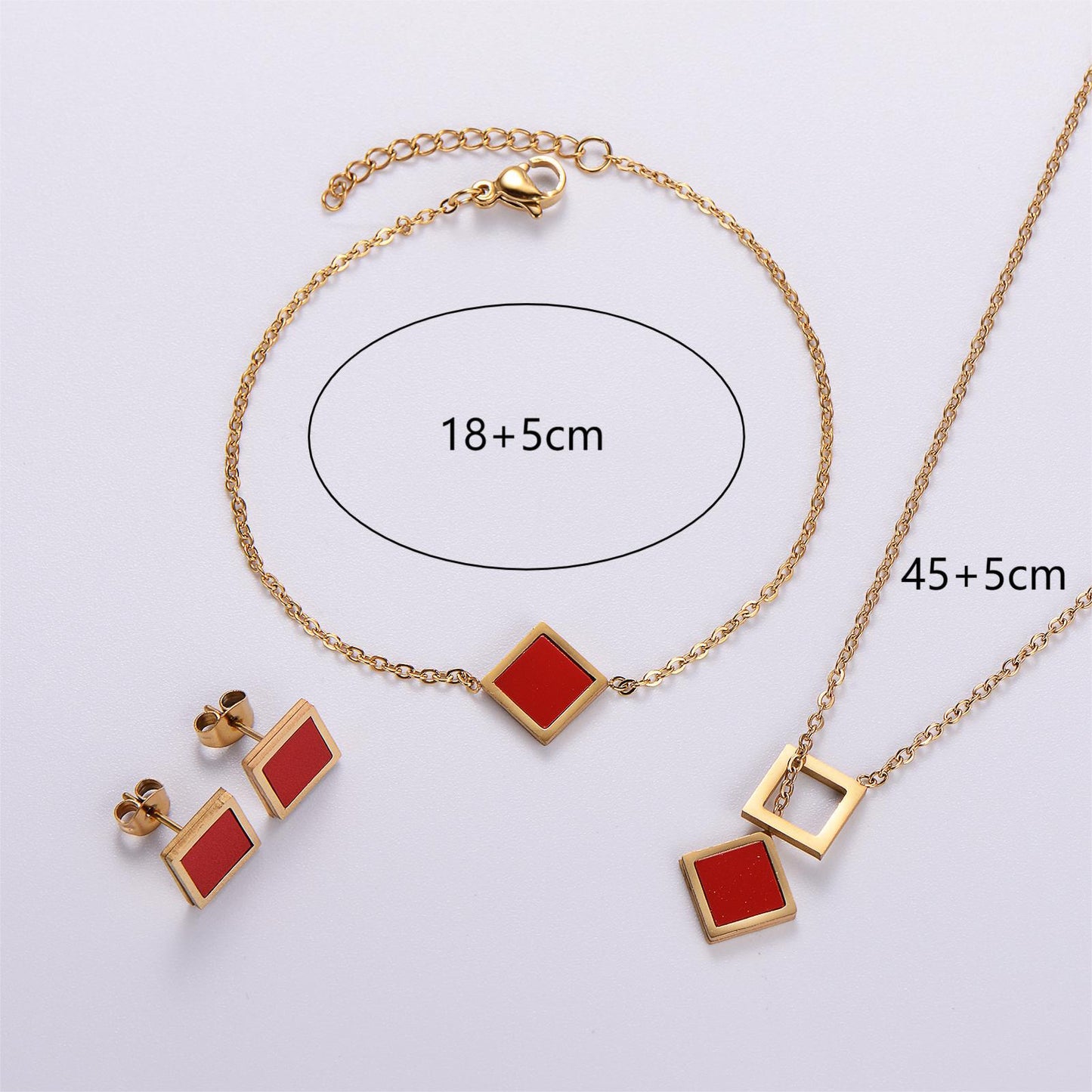 Gold jewelry set with red square stones on a white background