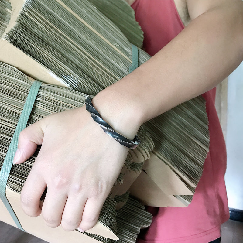 Person holding a stack of green folders with a bracelet on wrist