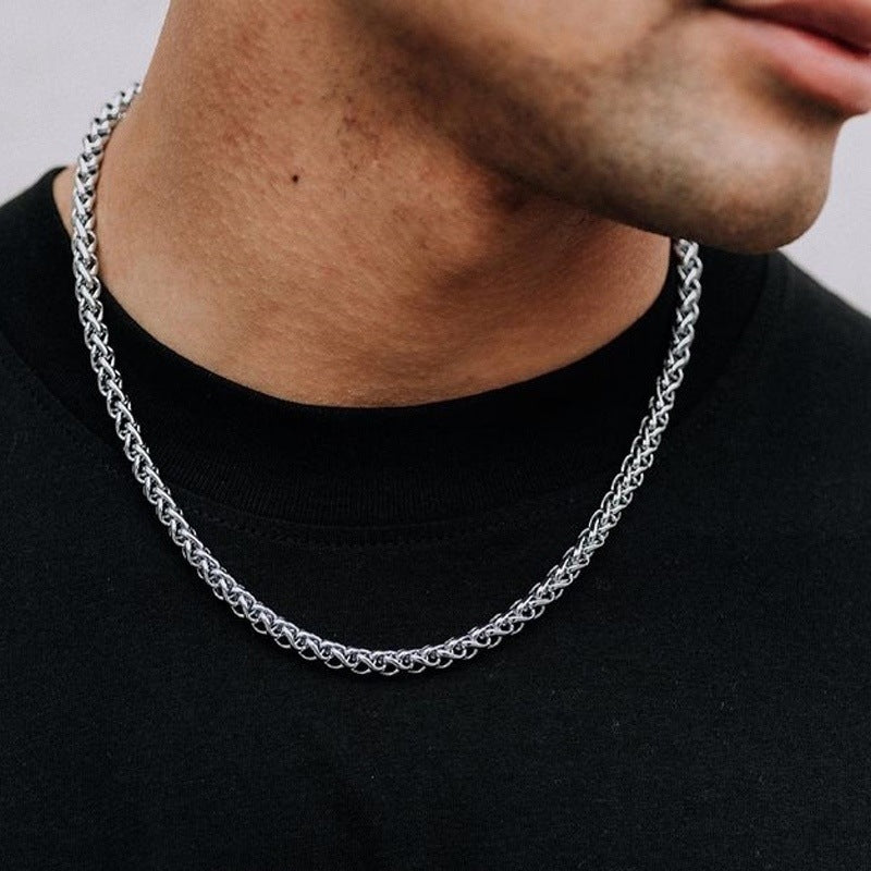 Silver chain necklace worn by a person on a plain background