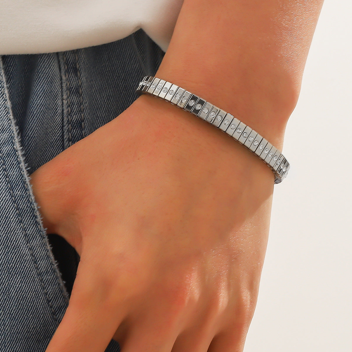 Silver bracelet on a wrist with a neutral background