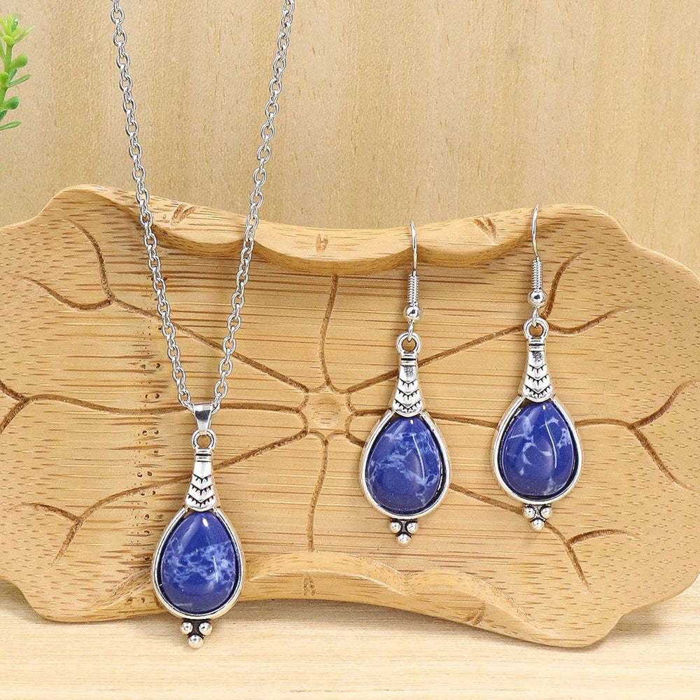 Jewelry set with blue teardrop pendants on a wooden surface