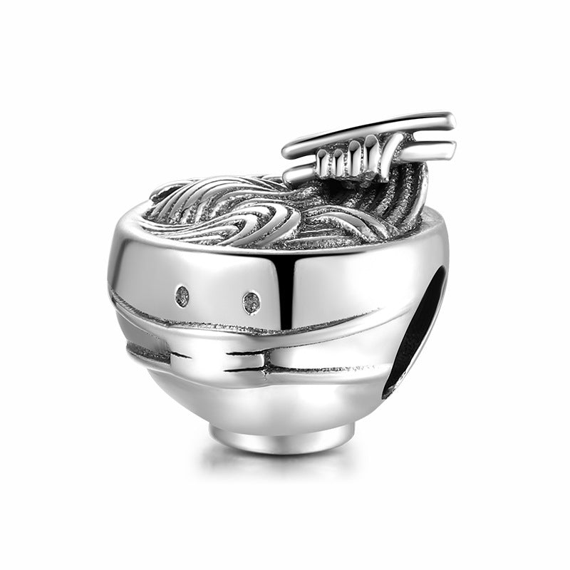 Silver charm shaped like a bowl of ramen with chopsticks on a white background