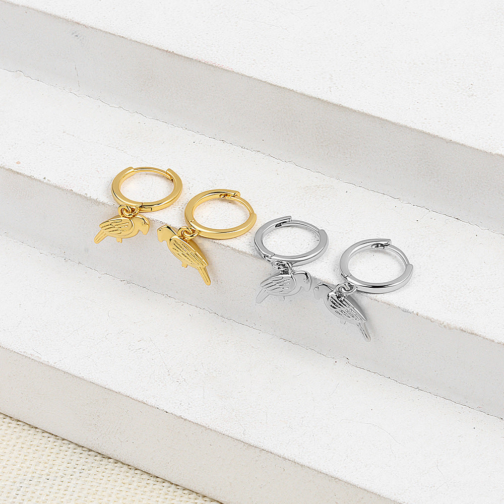 Gold and silver hoop earrings with angel wing charms on a white surface.