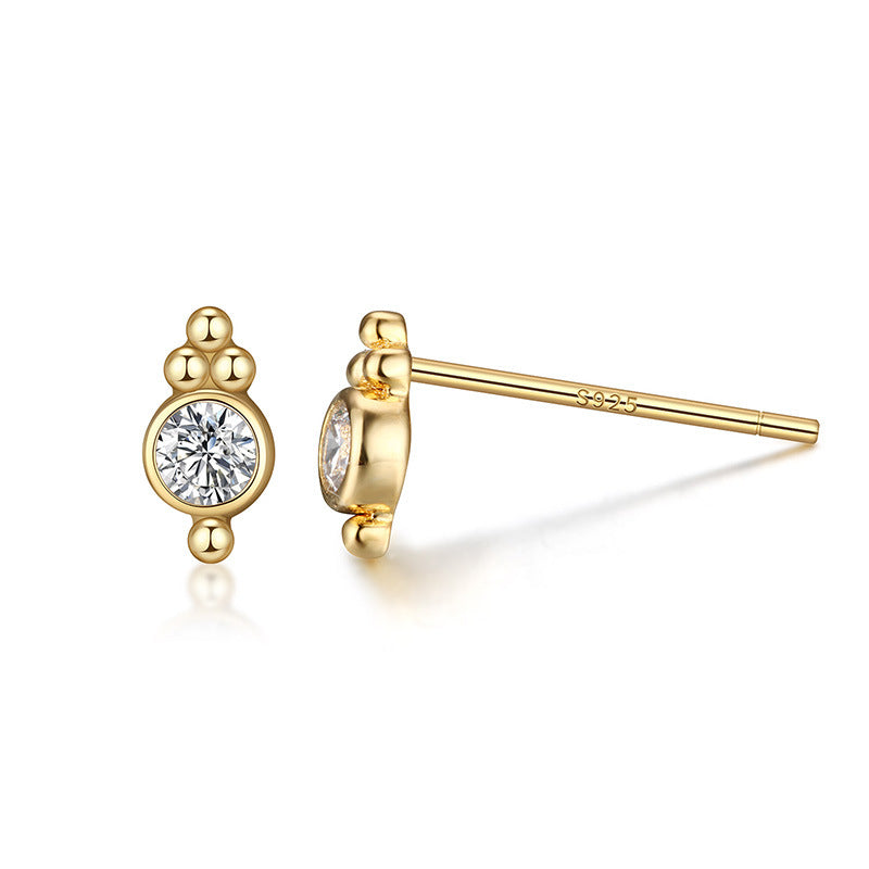 Gold earrings with clear gemstones on a white background