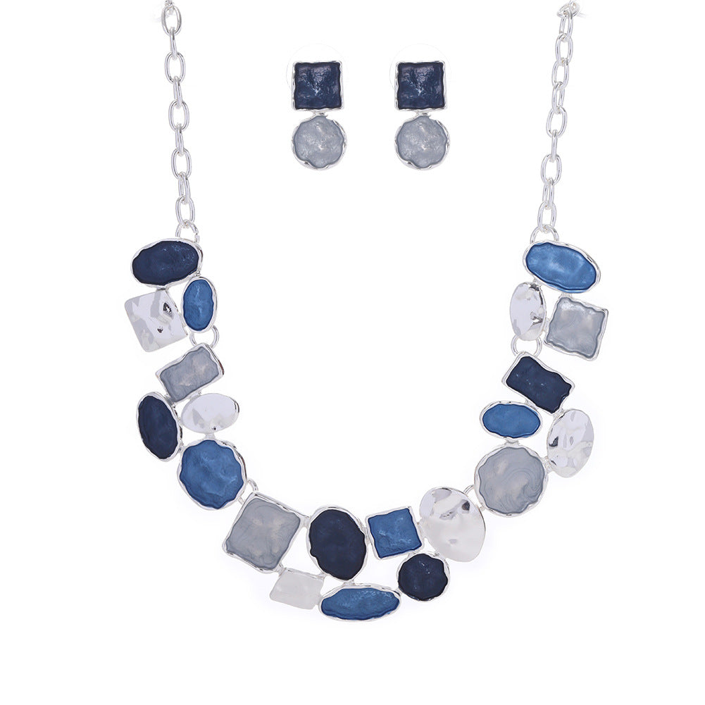 Necklace and earrings set with blue and gray stones on a white background