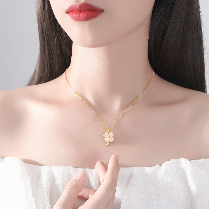 Woman wearing a gold necklace with a floral pendant against a neutral background