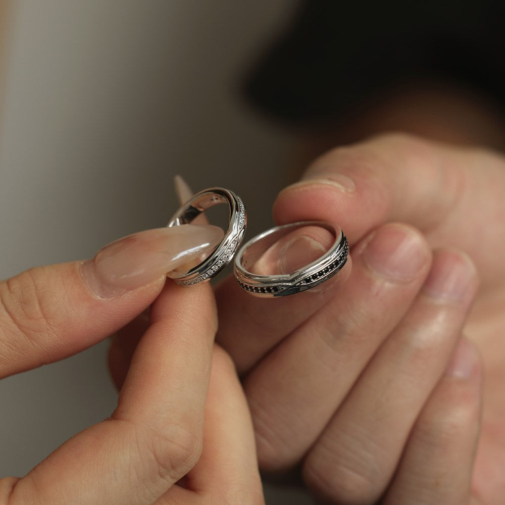Two silver rings held between fingers against a neutral background